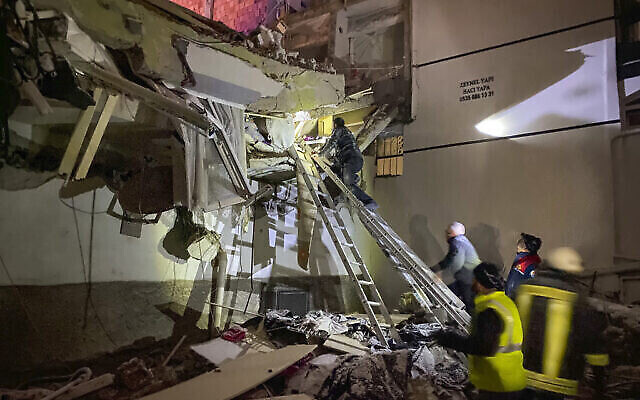 تصویر: گروه امداد در روز ۶ فوریهٔ ۲۰۲۳ تلاش می-کند به ساکنانی که در خانهٔ زلزله-زده در آدانا گیر کرده-اند، کمک کند. (IHA agency via AP)