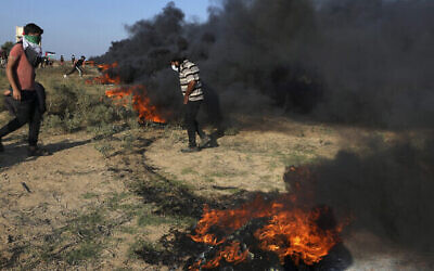 تصویر: معترضان فلسطینی در ۲۲ سپتامبر ۲۰۲۳، حین زدوخورد با نیروهای امنیتی فلسطینی در جبههٔ اسرائیل، شرق شهر غزه، لاستیک آتش می-زنند. (AP Photo/Adel Hana)