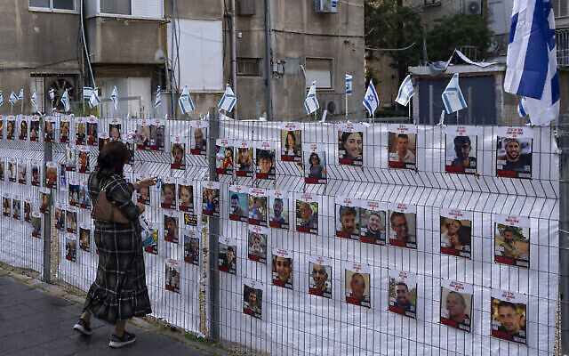 تصویر: زنی در ۲۲ نوامبر ۲۰۲۳ در رمت گن به تصویر گروگانهای غزه که به دیوار نصب شده نگاه می-کند.
(AP Photo/Oded Balilty)