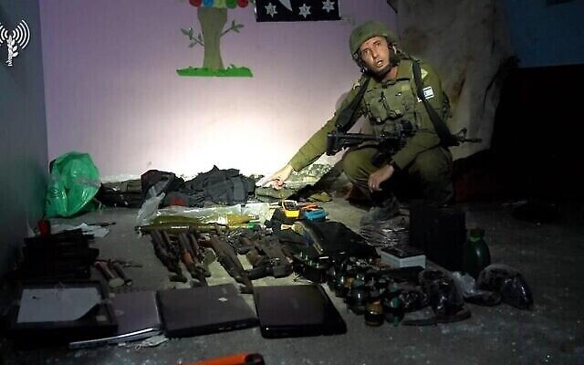 تصویر: دانیل هگاری سخنگوی نیروهای دفاعی بهمراه اسلحه-هایی که نیروهای دفاعی در مرکز فرماندهی حماس زیر بیمارستان رنتیسی شهر یافتند. ارتش اسرائیل این عکس را در ۱۳ نوامبر ۲۰۲۳ منتشر کرد. (Israel Defense Forces)