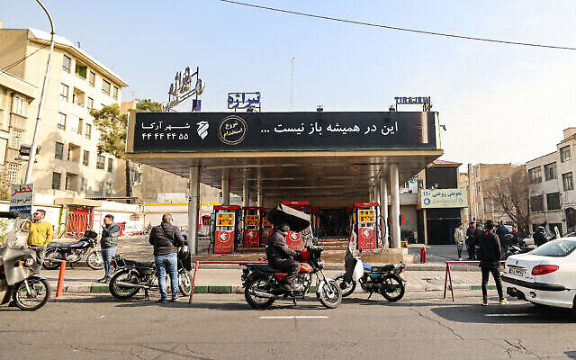 تصویر: مردم در ۱۸ دسامبر ۲۰۲۳، در یکی از جایگاههای فروش بنزین در تهران، منتظر ایستاده-اند.  بنا به گزارش روزنامهٔ رسمی، ۷۰ درصد جایگاههای فروش بنزین «احتمالاً بعلت خرابکاری» دچار اختلال شده-اند. (ATTA KENARE / AFP)