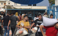 تصویر:‌ مردم فلسطین در ۲۸ اکتبر ۲۰۲۳ یک مرکز توزیع کمکهای بشردوستانهٔ سازمان ملل در دیر البلاح، که میان خانواده-های آوارهٔ نوار غزه مواد غذایی پخش می-کند را غارت کردند. (Mohammed Abed / AFP)