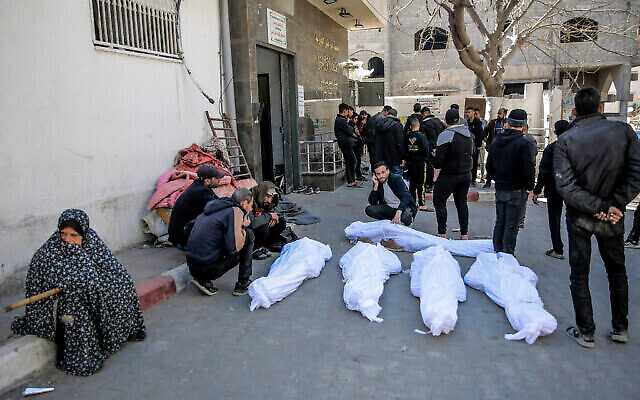 تصویر: مردم در مقابل بیمارستان الشفای شهر غزه، ۲۹ فوریه ۲۰۲۴، بر سر جسد فلسطینی-هایی که سحرگاه هنگام شتاب به سمت کامیونهای حامل کمک کشته شدند، سوگواری می-کنند. (AFP)