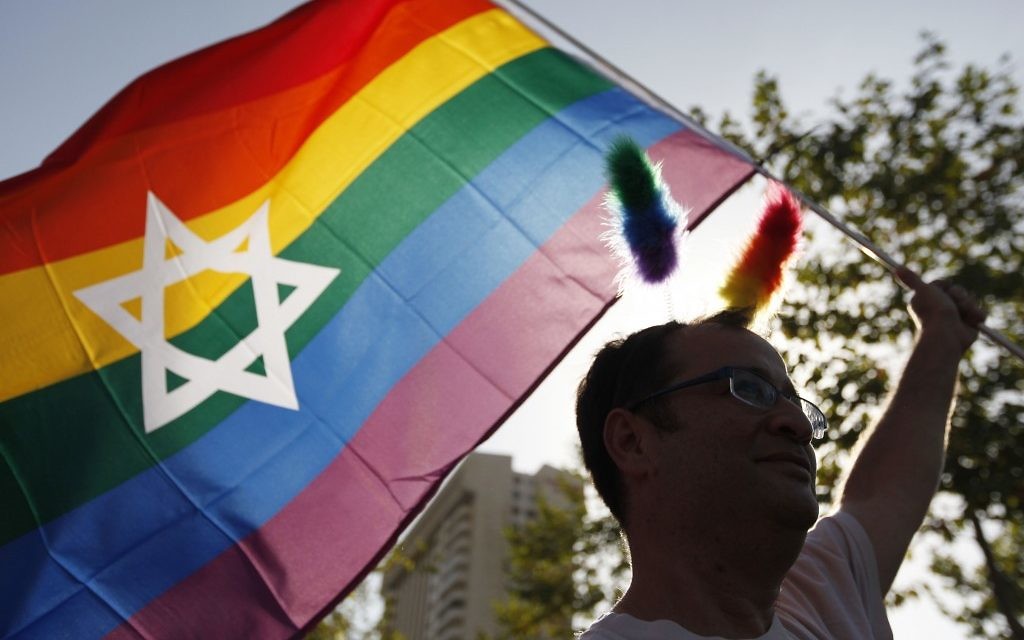Un homme agite un drapeau arc-en-ciel à la Gay Pride de Jérusalem (Crédit : Miriam Alster / FLASH90)