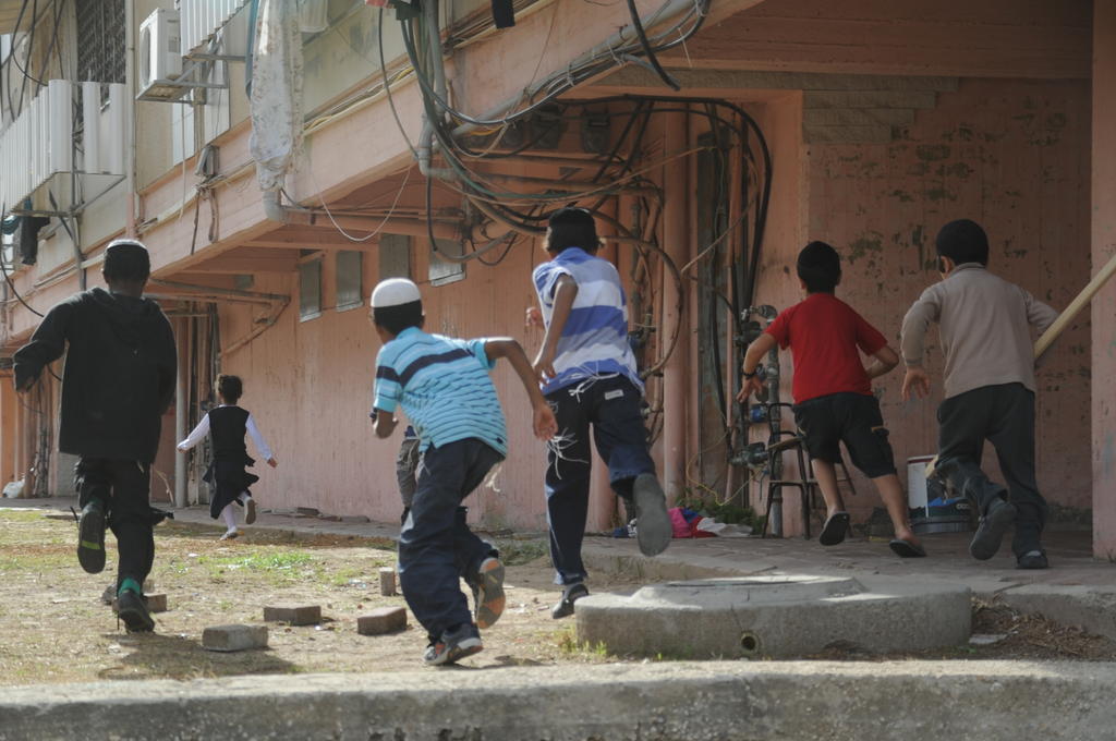 Children in Kiryat Malachi run toward a bomb shelter Friday. A residential building in the southern city was hit by a rocket Thursday, killing three. (photo credit: IDF Spokesperson)