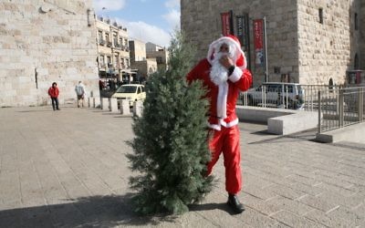 Un homme habillé en Père Noël avec un sapin de Noël, porte de Jaffa, devant la Vieille Ville de Jérusalem, en décembre 2008. Illustration. (Crédit : Yossi Zamir/Flash90)
