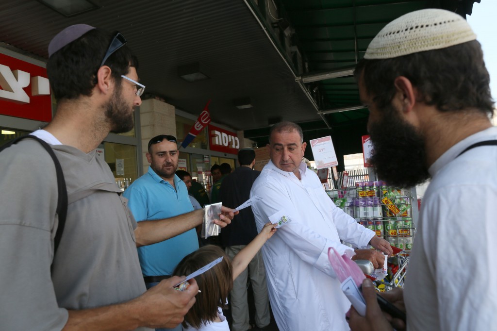 Members of Eretz Shalom movement giving candy to Arab shoppers as they mark the last Friday prayers of Ramadan, at the Rami Levy supermarket in Gush Etzion on August 17, 2012. (photo credit: Nati Shohat/Flash90)