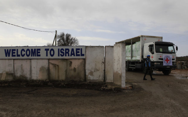 Les soldats de l'ONU regardent un camion de la Croix-rouge internationale chargé de pommes traverser le poste-frontière de Quneitra entre le plateau du Golan israélien et la Syrie en février 2011 (Crédit :  Tsafrir Abayov/Flash90)