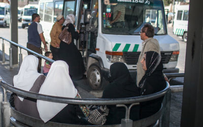 Des Palestiniens montent à bord d'un bus en direction de Ramallah vers la gare centrale des bus à Jérusalem Est (Crédit : Noam Moskowitz)