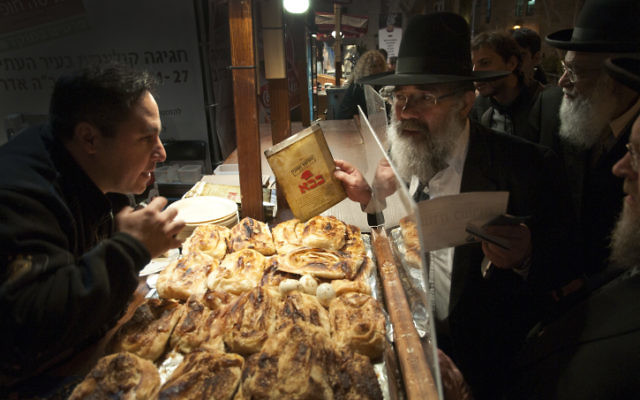 Un représentant du Grand Rabbinat inspecte un certificat de casheroute suspect dans un stand d'alimentation, Jérusalem, le 28 mars 2011. (Crédit : Rubin Salvadori/Flash90)