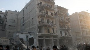 Des habitants devant un immeuble touché par une attaque aérienne de l'armée syrienne, le 29 janvier 2014 à Alep (Crédit : AFP/Mohammed Al-Khatieb)