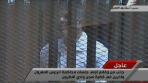 Capture d'image de la télévision égyptienne montrant le président déchu Mohamed Morsi derrière le grillage d'une cage pendant son procès, le 28 janvier 2014 au Caire  (Crédit : Télévision égyptienne/AFP)