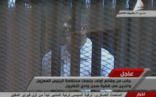 Capture d'image de la télévision égyptienne montrant le président déchu Mohamed Morsi derrière le grillage d'une cage pendant son procès, le 28 janvier 2014 au Caire 
(Crédit : Télévision égyptienne/AFP)