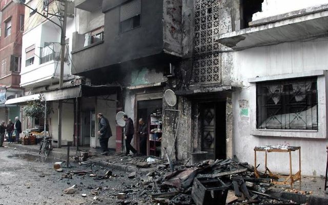 Des habitants dans une rue de Homs après des tirs au mortier de rebelles syriens, le 9 janvier 2014 
(Crédit : Sana/AFP/Archives)
