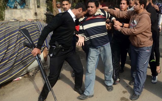 Un policier arrête un partisan des Frères musulmans le 25 janvier 2014 au Caire (Crédit AFP/Mohamed el-Shahed)