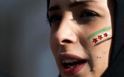 Vendredi 24 janvier 2014, devant le siège de l'Onu à Genève, une manifestante contre le régime de Bachar al-Assad, maquillée aux couleurs nationales syriennes. (Crédit : AFP/Fabrice Coffini)