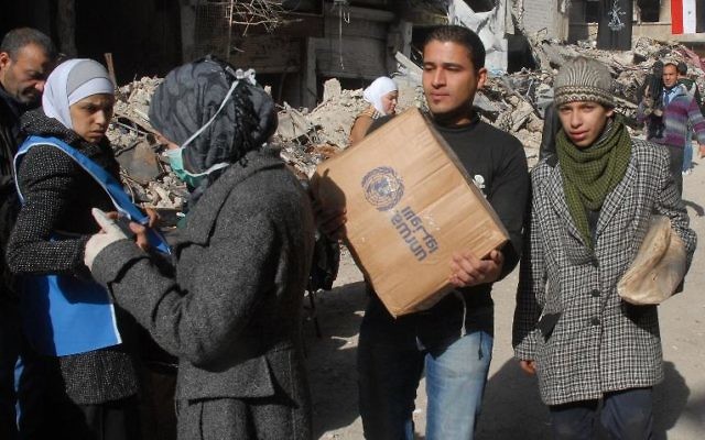 Des réfugiés palestiniens du camp de Yarmouk, au sud de Damas, reçoivent de l'aide alimentaire, le 30 janvier 2014 (Crédit: Sana/AFP)