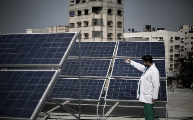 Un médecin palestinien montre les panneaux solaires installés sur les toits de l'hôpital des enfants à Gaza, 24 février 2014 (Crédit : Mahmud Hams/AFP)