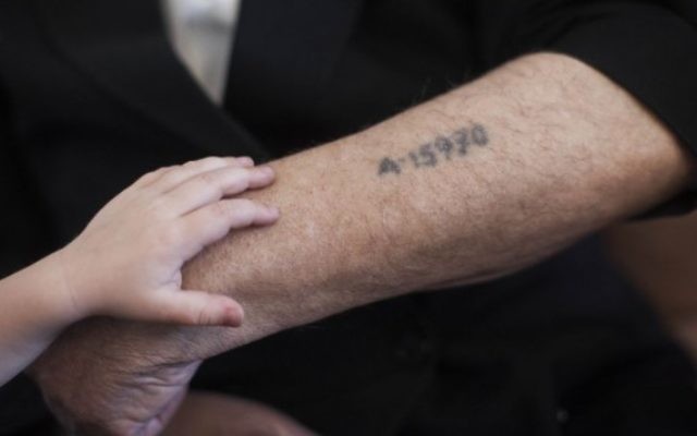 Un petit garçon met sa main sur le bras de son grand-père, près de son tatouage de prisonnier de camp de concentration, à Jérusalem, le 24 mai 2013. (Crédit : Yonatan Sindel/Flash90)