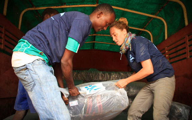 Une volontaire aide à décharger les dons de l'organisation IsraAID au camp de réfugiés de Kakuma au Kenya (Crédit : Autorisation d'IsraAID)