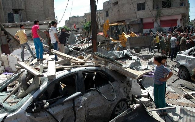Le personnel d'urgence et les civils inspectent les lieux suite à l'attentat à la voiture piégée dans le quartier d'Abbasiyah dans la ville syrienne de Homs, le 29 avril 2014 (Crédit : AFP Photo)