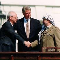 La poignée de main entre Yitzhak Rabin et Yasser Arafat, accompagnés de Bill Clinton, après la signature des Accords d'Oslo, le 13 septembre 1993. (Crédit : Vince Musi/The White House/Wikimedia commons)