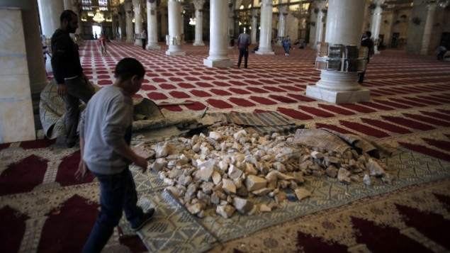 Des pierres stockées à l'intérieur de la mosquée d'Al-Aqsa, qu'un employé tente de nettoyer, en 2014. (Crédit : AFP/Ahmad Gharabli)