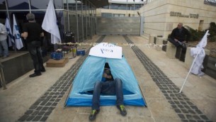 Un salarié du ministère des Affaires étrangères étendu dans une tente alors qu'il fait grève devant des bureaux du ministère, le 24 mars 2014 (Crédit : Yonatan Sindel/Flash90) 