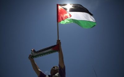 Un Palestinien arborant le drapeau palestinien (Crédit : AFP)