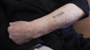 Un survivant de la Shoah montre son bras tatoué par les nazis. Illustration. (Crédit : Yonatan Sindel/Flash90)