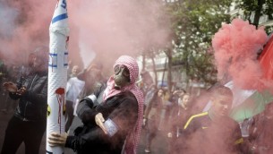 Un manifestant français à Paris qui fait une quenelle en portant un masque et une fausse roquette (Crédit : AFP)