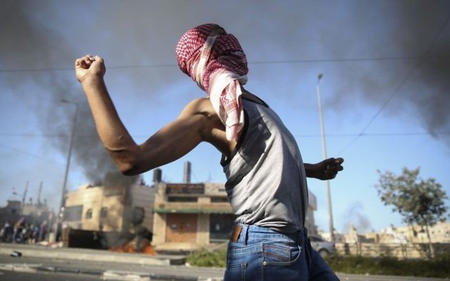 Un Palestinien lançant des pierres sur les autorités israéliennes (Crédit : Hadas Parush/Flash 90)