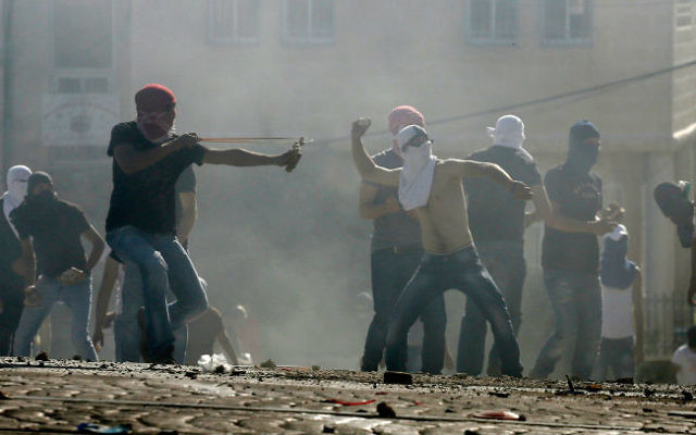 Des Palestiniens masqués en train de jeter des pierres sur la police à Jérusalem Est le 3 juillet 2014  (Crédit : Slimane Khader/Flash90)