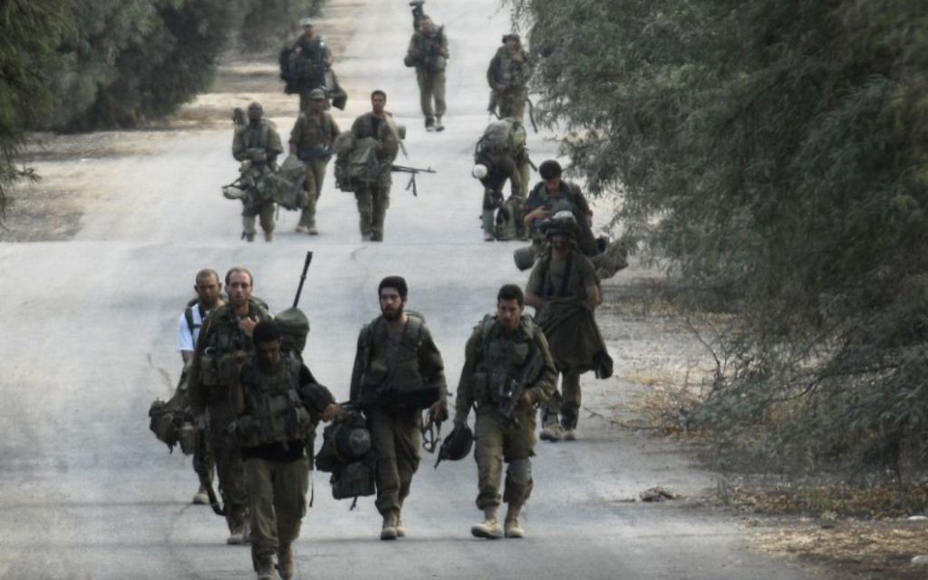 Soldats israéliens à pied près de la frontière entre Israël et la bande de Gaza qui reviennent de l'enclave côtière palestinienne contrôlée par le Hamas, le mardi 5 août 2014 (Crédit : AFP / DAVID BUIMOVITCH)