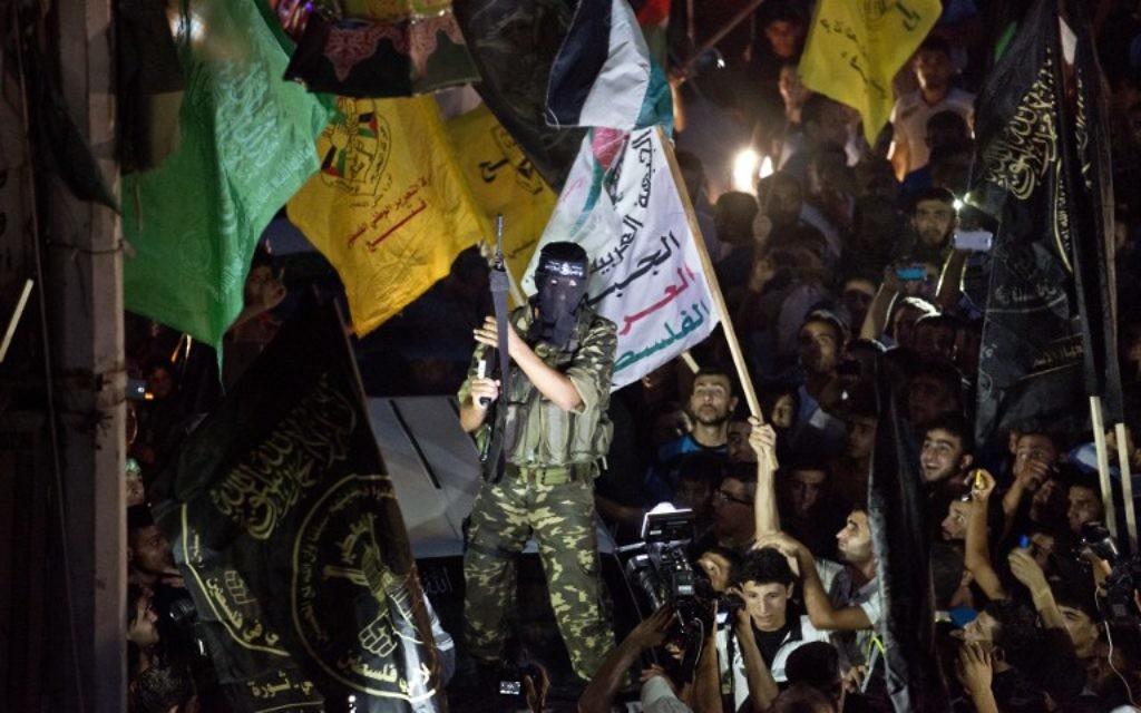 Un militant brandit son arme alors qu'il tire des coups de feu en l'air après avoir rejoint des centaines d'habitants de Gaza, le 26 août 2014 pour célébrer un accord de cessez-le-feu conclu entre Israël et le Hamas. (Crédit : AFP PHOTO / ROBERTO SCHMIDT)