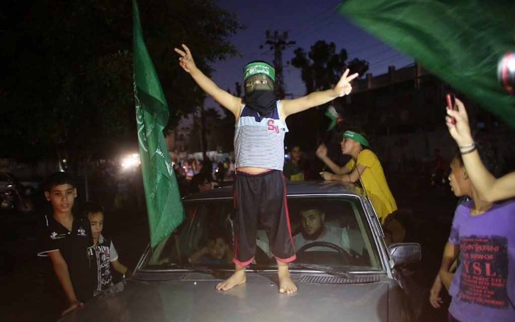 Un enfant palestinien avec un bandeau du Hamas fait le signe de la victoire sur une voiture alors que les gens se rassemblent dans les rues pour célébrer l'accord de trêve conclu entre le Hamas et Israël, à Rafah, dans le sud de la bande de Gaza, le 26 août 2014. (Crédit : AFP PHOTO / SAID KHATIB)