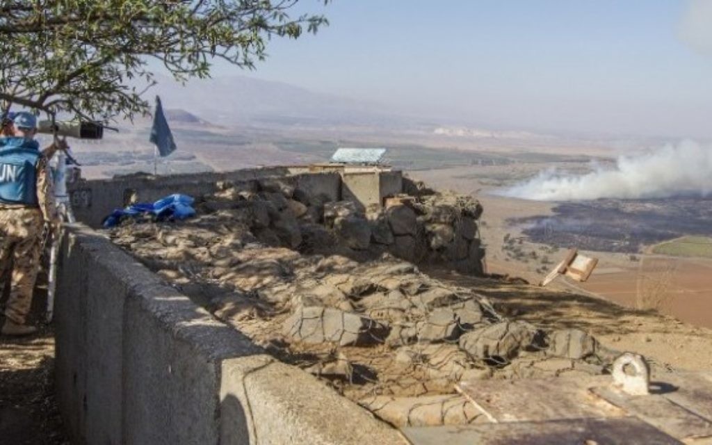 Des forces de la FNUOD de maintien de la paix des Nations unies utilisent des jumelles pour regarder la fumée s'élever au loin causée par les combats entre les forces loyales au président syrien Bashar el-Assad et les rebelles pour le contrôle de la frontière de Qouneitra, le 27 août 2014 (Crédit : Jack Guez / AFP)