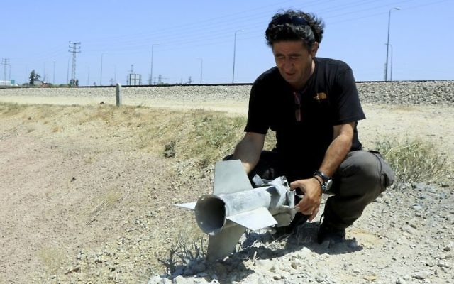 Un homme tient une partie d'une roquette qui a explosé et est tombée à l'intérieur de la frontière israélienne avec la bande de Gaza le 20 août, 2014 (Crédit : Edi Israël / Flash90)