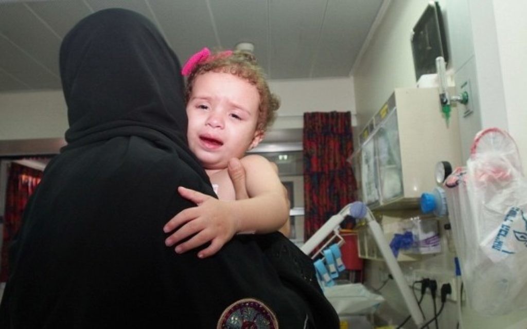 Hala Arada, âgée de deux ans,  avec sa grand-mère Haniyeh Shaer à l'hôpital Wolfson à Holon, le 12 août 2014. Hala a une maladie cardiaque congénitale et est traitée en Israël. Deux membres de sa famille ont récemment été tués dans un raid aérien israélien à Gaza. (Crédit : Sheila Shalhevet / Save a Child's heart)