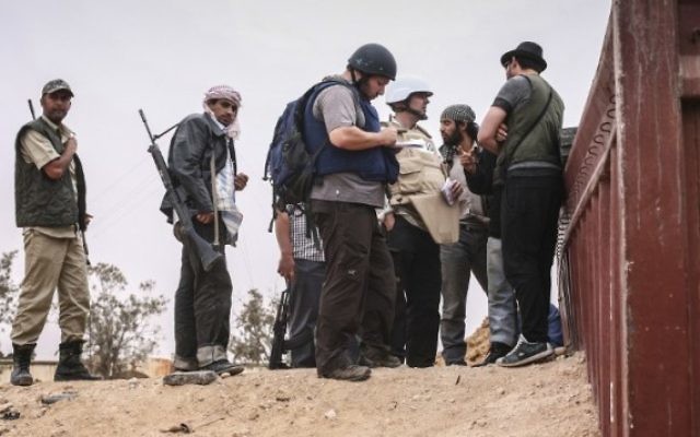 Steven Sotloff (au centre avec un casque noir) discutant avec des rebelles libyens, le 2 juin 2011.(Crédit : autorisation Etienne de Malgraive, via AFP)