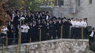 Des Israéliens regardent le lieu de l'attentat terroriste contre la synagogue d'Hart Nof - 18 novembre 2014 (Crédit : Jack Guez/AFP)