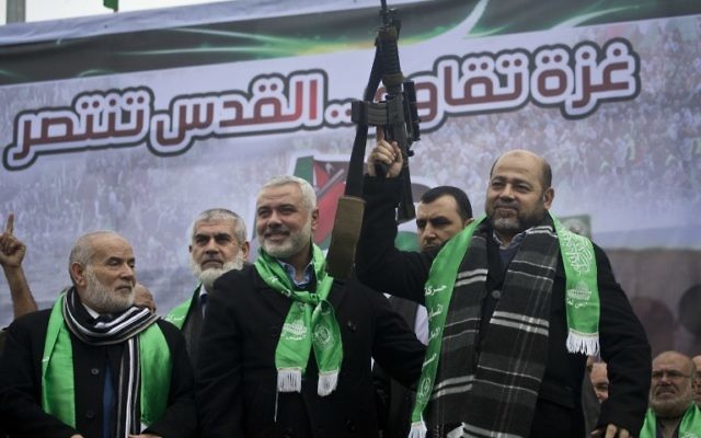 Les dirigeants du Hamas de Gaza Ismail Haniyeh, (au centre) et Mousa Abu Marzouq, à droite, brandissent une arme et saluent leurs partisans pendant une cérémonie marquant le 27e anniversaire de la création du mouvement islamiste le 14 décembre 2014 dans la ville de Gaza. (Crédit : AFP / MAHMUD HAMS)