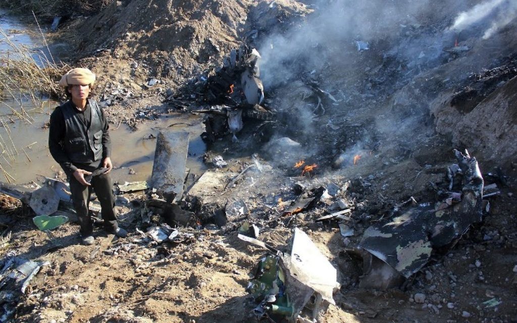 Un combattant de l'Etat islamique collecterait des pièces à partir des restes d'un avion de guerre jordanien de la coalition dirigée par les Etats-Unis qui a été abattu dans la région de Rakka en Syrie, le 24 décembre 2014. (Crédit : AFP/RMC/STR)