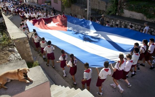 De jeunes élèves portant le drapeau cubain lors d'un défilé dans les rues de Gibara à Cuba le 20 janvier 2014 (Crédit : Moshe Fai/Flash90))