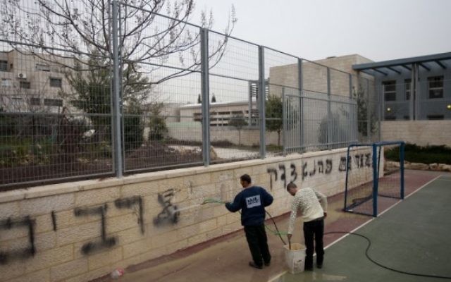 Les travailleurs nettoyant des graffitis racistes de l'école bilingue le 7 février 2012 (Crédit :  Flash90)