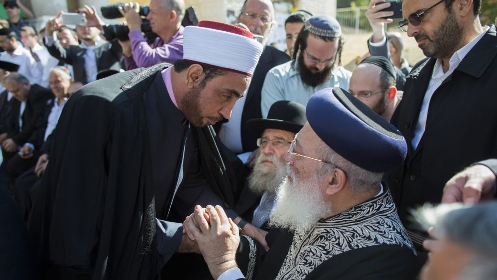 Rabbi Shlomo Amar (assis à droite) sert la main d'un imam lors d'une cérémonie où les leaders chrétiens et musulmans ont montré leur soutien envers la communauté juive suite à l'attaque d'Har Nof (Crédit : Yonathan Sindel/Flash90)