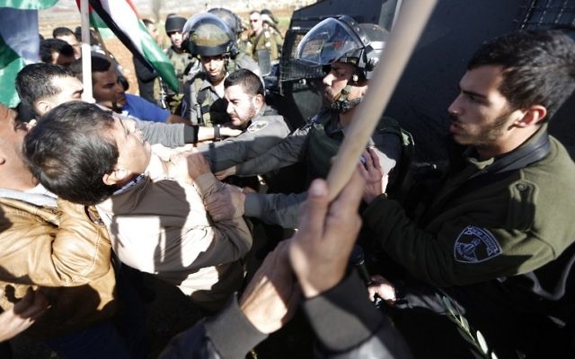 Un agent de la police des frontières attrape le fonctionnaire de l'AP (à gauche) lors d'une manifestation en Cisjordanie le 10 décembre (Crédit : AFP/Abbas Momani)