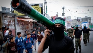 Une homme masqué du Hamas portant une fausse roquette (Crédit : Abed Rahim Khatib/Flash90)