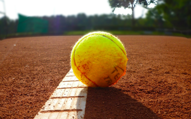 Illustration d'une balle de tennis sur un court de tennis de terre battue (Crédit : Pixabay)