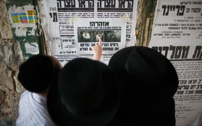 Des Juifs ultra-orthodoxes lisent le journal dans une rue du quartier de Mea Shearim (Crédit : Yonathan Sindel/Flash 90)